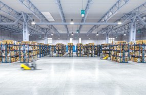 Valokuva suuresta varastosta, jossa on kaksi liikkuvaa trukkia. 