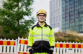 Kuva Jaakko Heinosta, hän seisoo työmaa-alueella työvaateet päällä.