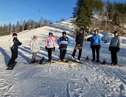 Laskettelijoita poseeraamassa vierekkäin rinteessä.