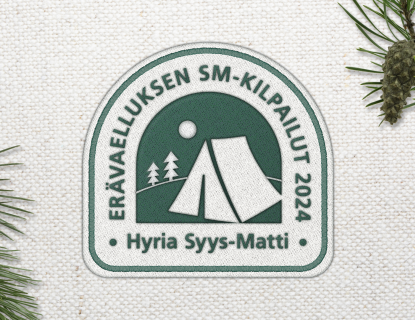 Syysmatti-logo. Logossa väreinä tummanvihreä ja beige. Logossa on kuvituksena beige teltan kuva tummanvihreällä taustalla. 